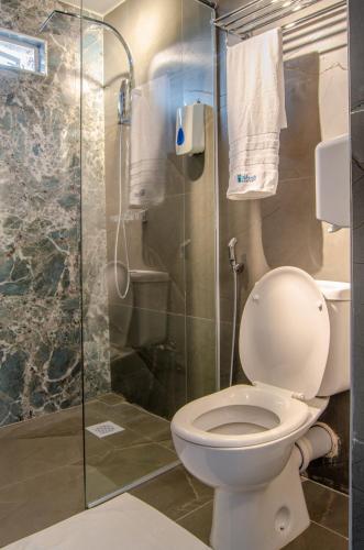 a bathroom with a toilet and a glass shower at La Fattoria Resort in Mombasa
