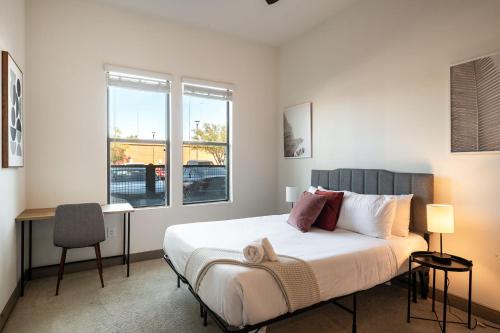 a bedroom with a bed and a desk and windows at Modern CozySuites on the Town Lake waterfront 12 in Tempe