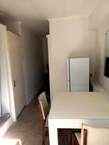 a kitchen with a white table and a refrigerator at Ocean Walk Garrick in Zinkwazi Beach