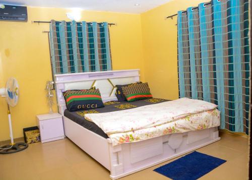 una camera da letto con un letto bianco con tende blu di Rehoboth hotel, Apartment and Event services a Suberu Oje