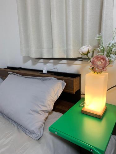 a bed with a green table with a vase with a flower at 孔雀民宿 in Osaka