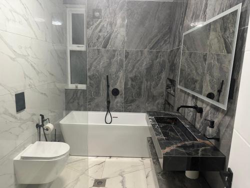 a bathroom with a white tub and a toilet at Luxurious & Elegant 6-Bed House in Barnet