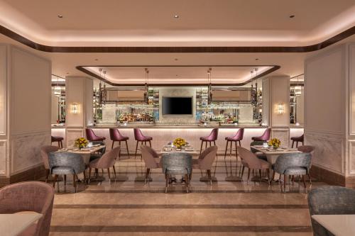 a restaurant with tables and chairs and a bar at Aurika, Mumbai International Airport - Luxury by Lemon Tree Hotels in Mumbai