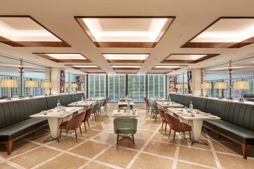 a restaurant with tables and chairs and windows at Aurika, Mumbai International Airport - Luxury by Lemon Tree Hotels in Mumbai