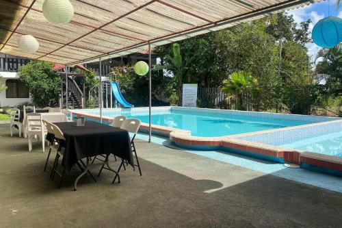 a swimming pool with a table and chairs next to a swimming pool at Hotel y restaurante Tabaconess in Guácimo