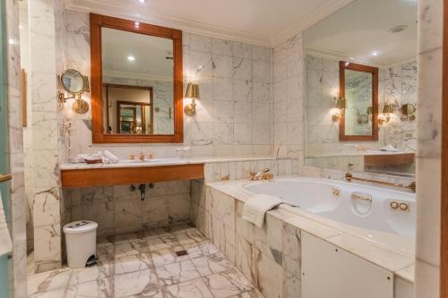 een badkamer met een bad, een wastafel en een spiegel bij The Subic Bay Yacht Club, Inc. in Olongapo