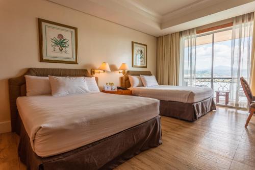 a hotel room with two beds and a balcony at The Subic Bay Yacht Club, Inc. in Olongapo