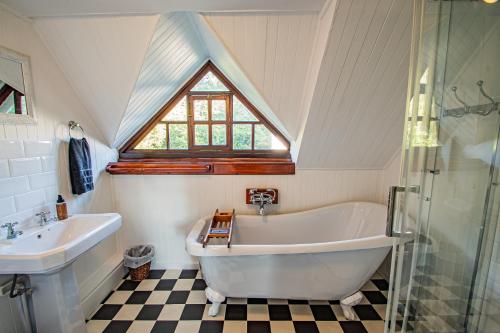 baño con bañera, lavabo y ventana en Crossroads Cottage, en Dullstroom