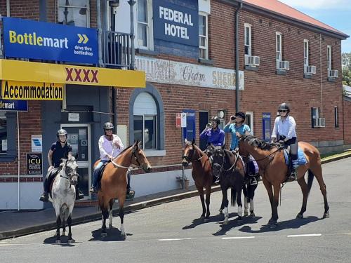 a group of people riding horses down a street at Federal Hotel in Quirindi