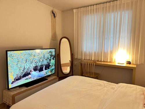 a bedroom with a bed and a large flat screen tv at Athome - Foreigner Only in Seoul