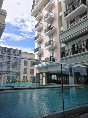 a building with a swimming pool in front of a building at Saint Honore Executive 1 Full bed, 1 Sofa bed 1 Pull out bed 2BR in Iloilo City