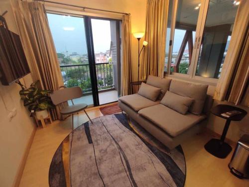 a living room with a couch and a large window at Central Comfy Airy Tidy Apartment in Udon Thani