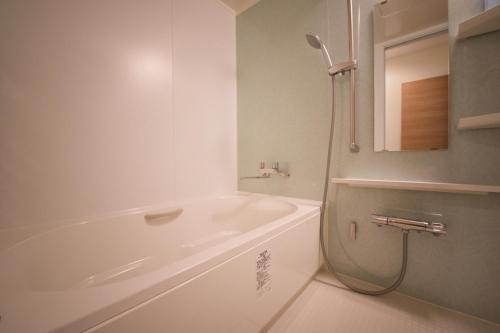 een witte badkamer met een bad en een douche bij Ryoan / Vacation STAY 80251 in Otaru