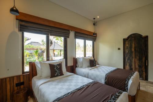 two beds in a room with a window at Oma Ubud in Ubud