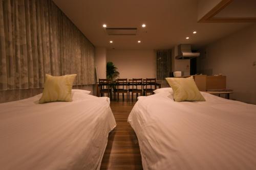 two beds in a room with a dining room at Ryoan / Vacation STAY 80261 in Otaru