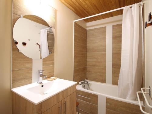 une salle de bain avec un lavabo, une baignoire et un miroir dans l'établissement Mont-Dore : Duplex T3 avec Parking, à 300m du centre - FR-1-608-268, à Le Mont-Dore