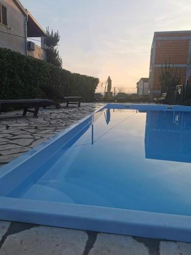 a blue swimming pool with a sunset in the background at Mobilehome Mali No 2 in Pakoštane