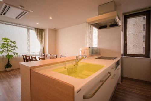 una cucina con lavandino giallo e tavolo di Ryoan / Vacation STAY 80269 a Otaru