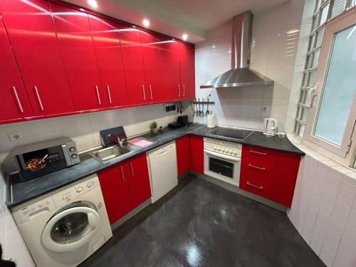 a kitchen with red cabinets and a washing machine at Habitaciones Magdalena in Madrid
