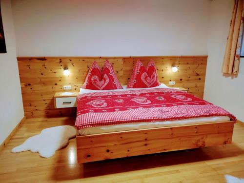 a bedroom with a wooden bed with red pillows at Ferienwohnung Familie Fiechtl in Fügenberg