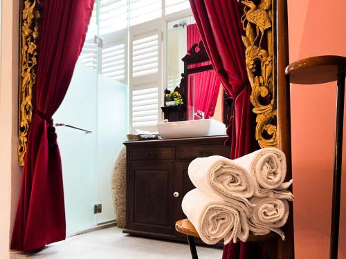 a room with a mirror and a chair with towels at Peranakan Suites Georgetown in George Town