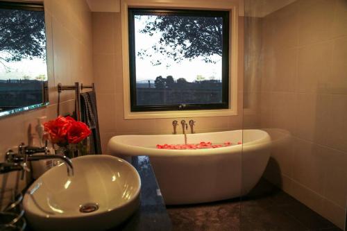 a bathroom with a tub and a sink and a window at Farmhouse on the Cradle Coast Forth in Forth