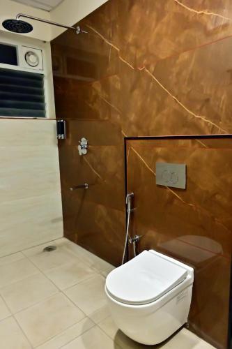 a bathroom with a toilet and a brown wall at DOWNTOWN The Mallika Sapphire in Chikmagalūr