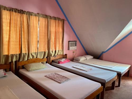 three beds in a room with a window at Oasis Resthouse in San Agustin