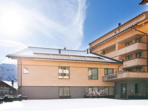 a large brick building with people sitting on a balcony at Apartment in Schröcken near Ski Arlberg in Schröcken