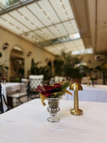 a vase with roses in it on a table with a gold bell at DBD Hotel Bayraklı in Bayrakli