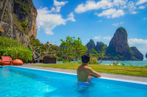 a man sitting in a swimming pool looking out at the ocean at Tinidee Hideaway Tonsai Beach Krabi - SHA Extra Plus in Tonsai Beach