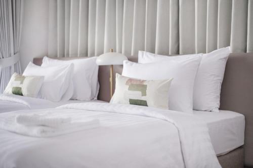 two beds with white sheets and pillows in a room at Unplugged at Bangrak Design Hostel in Bangkok