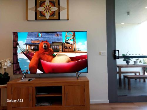 a tv screen with a bear sitting in a red chair at Lux 2 Bed 2 Bath Secure Parking Apartment in the Heart of Dickson, Canberra in Canberra