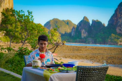 a man sitting at a table with a plate of food at Tinidee Hideaway Tonsai Beach Krabi - SHA Extra Plus in Tonsai Beach