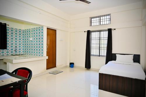 a bedroom with a bed and a desk and a window at Queen's Residency in Guwahati