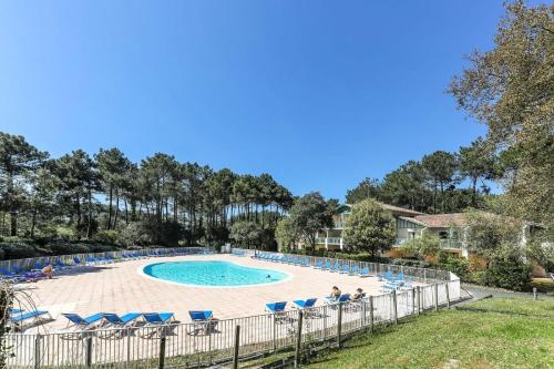 une piscine avec des chaises bleues et une clôture dans l'établissement Le Domaine du Golf de Pinsolle - maeva Home - Appartement 2 pièces 5 personnes - Prestige MAE-5704, à Soustons