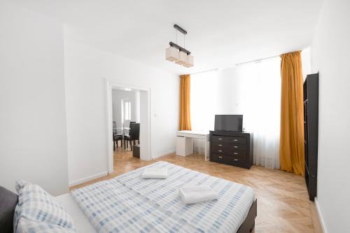 Your Home in Old Town Brasov في براشوف: غرفة نوم مع سرير وطاولة مع تلفزيون