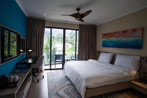 ein Schlafzimmer mit einem großen Bett und einem Balkon in der Unterkunft Thalassa Seychelles in Beau Vallon