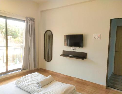 アリバグにあるCoastal Paradiseの壁にテレビとベッドが備わる客室です。