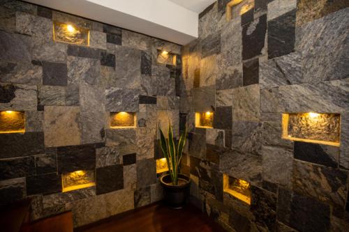 a room with a stone wall with lights at Manthra Leisure in Kandy