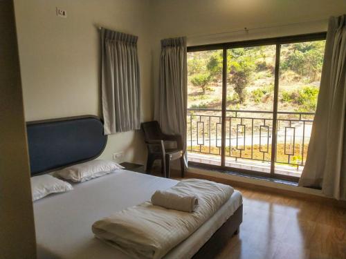 een slaapkamer met een bed en een groot raam bij Coastal Paradise in Alibaug
