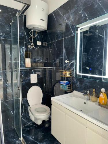 a bathroom with a toilet and a sink and a mirror at Holiday Apartment Aldi in Shëngjin