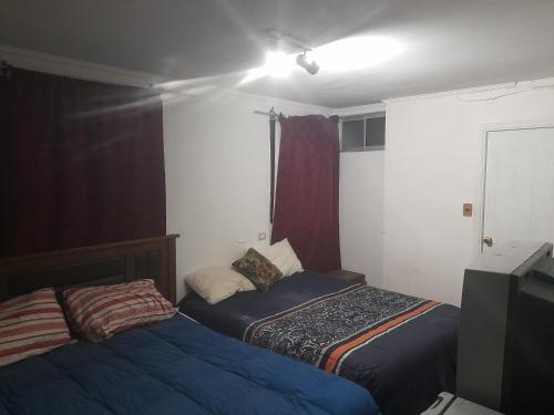 um quarto com duas camas e uma televisão em Hostal batuco em Viña del Mar
