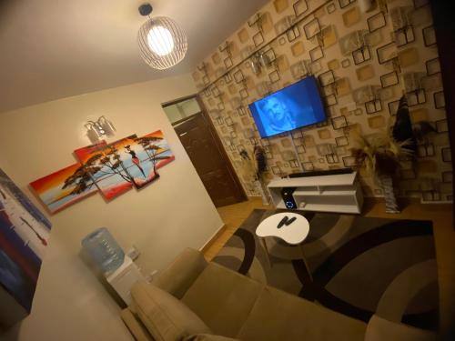 ein Wohnzimmer mit einem Sofa und einem TV in der Unterkunft Havana Apartments-South B in Nairobi