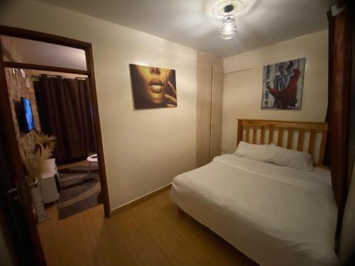 Schlafzimmer mit einem weißen Bett und einem Spiegel in der Unterkunft Havana Apartments-South B in Nairobi