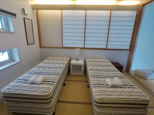 two twin beds in a room with a window at Hirafu House 7 in Ōmagari