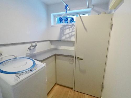 a small kitchen with a washing machine and a window at Hirafu House 7 in Ōmagari
