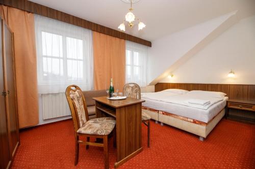 a bedroom with a bed and a desk and a table at Penzion Pomnenka in Luhačovice
