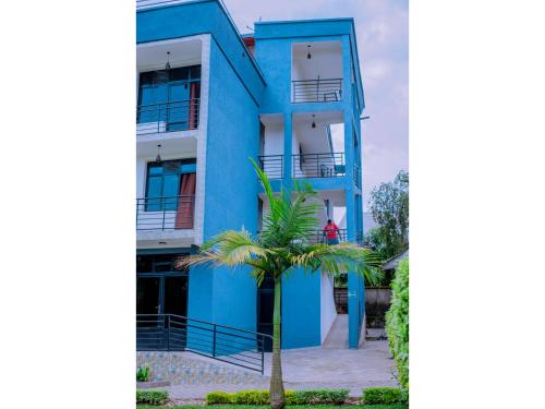 a blue building with a palm tree in front of it at Planete Hotel in Rubavu