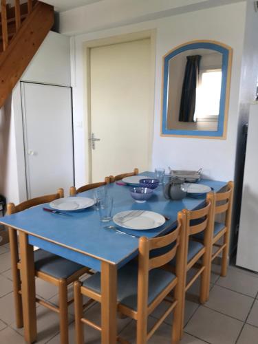 einem Esstisch mit Stühlen und einem blauen Tischtuch in der Unterkunft Maison en résidence avec piscine in Le Château-dʼOléron